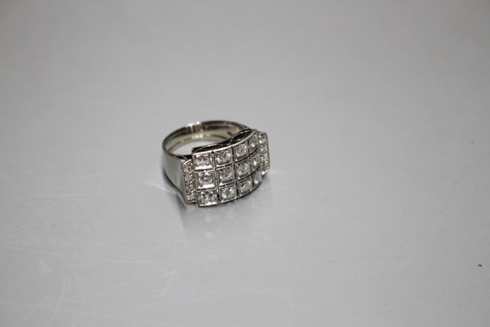 A white metal (stamped 750 and Pt 950) and pave diamond set cocktail ring, of curved design and set with twenty round cut stones.